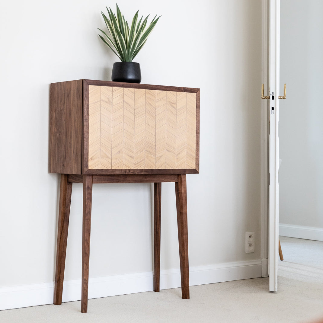 Wooden side table with a plant against a white wall