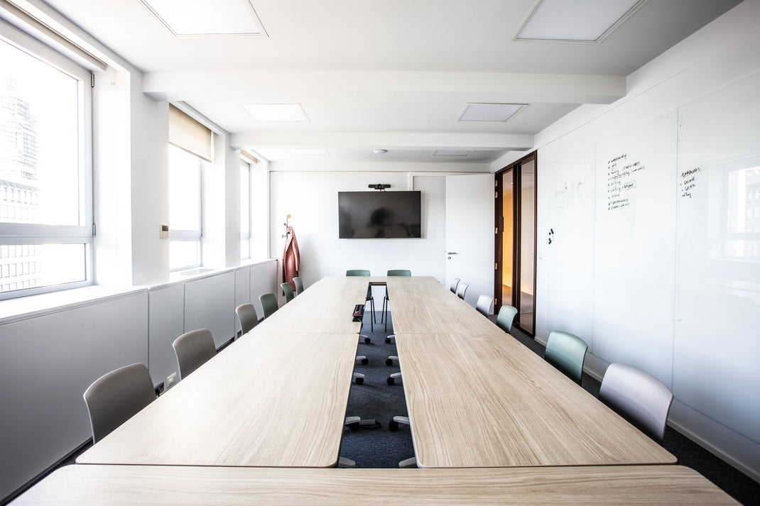 Modern conference room with long wooden table and chairs, large TV on the wall.