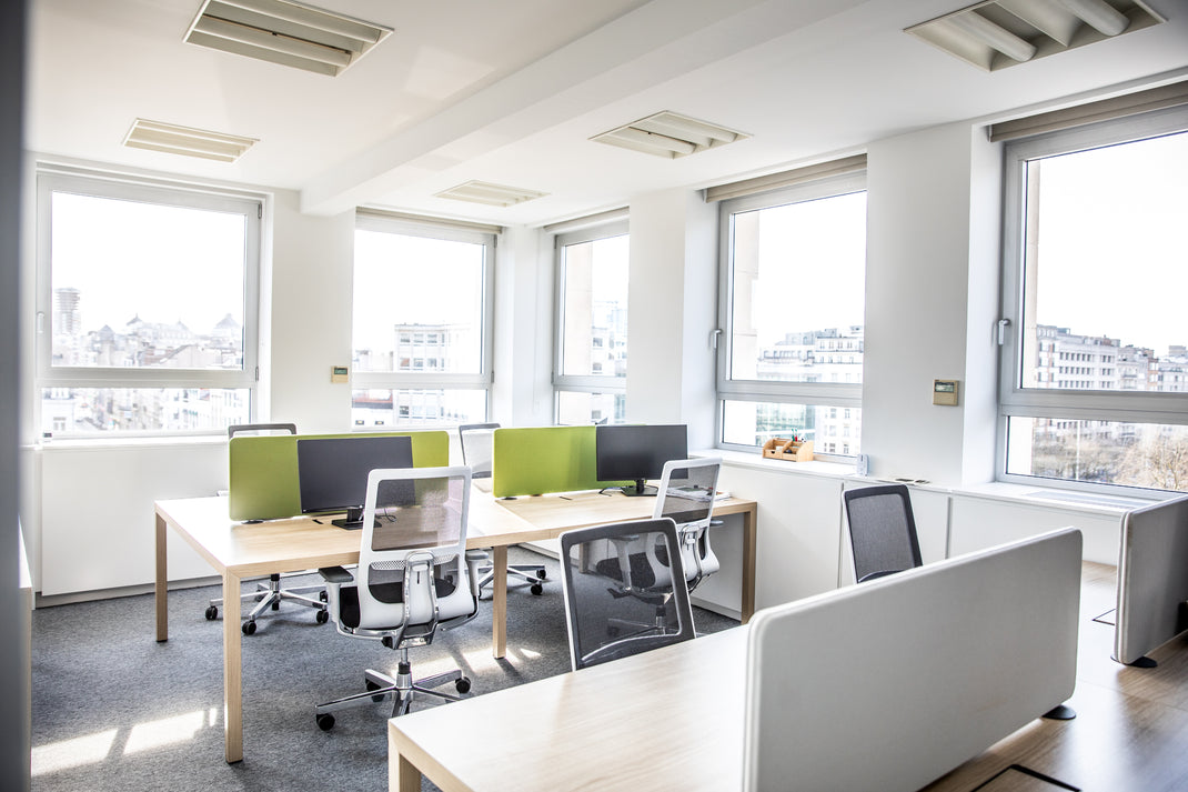 Modern open plan office space with desks, chairs, and large windows.