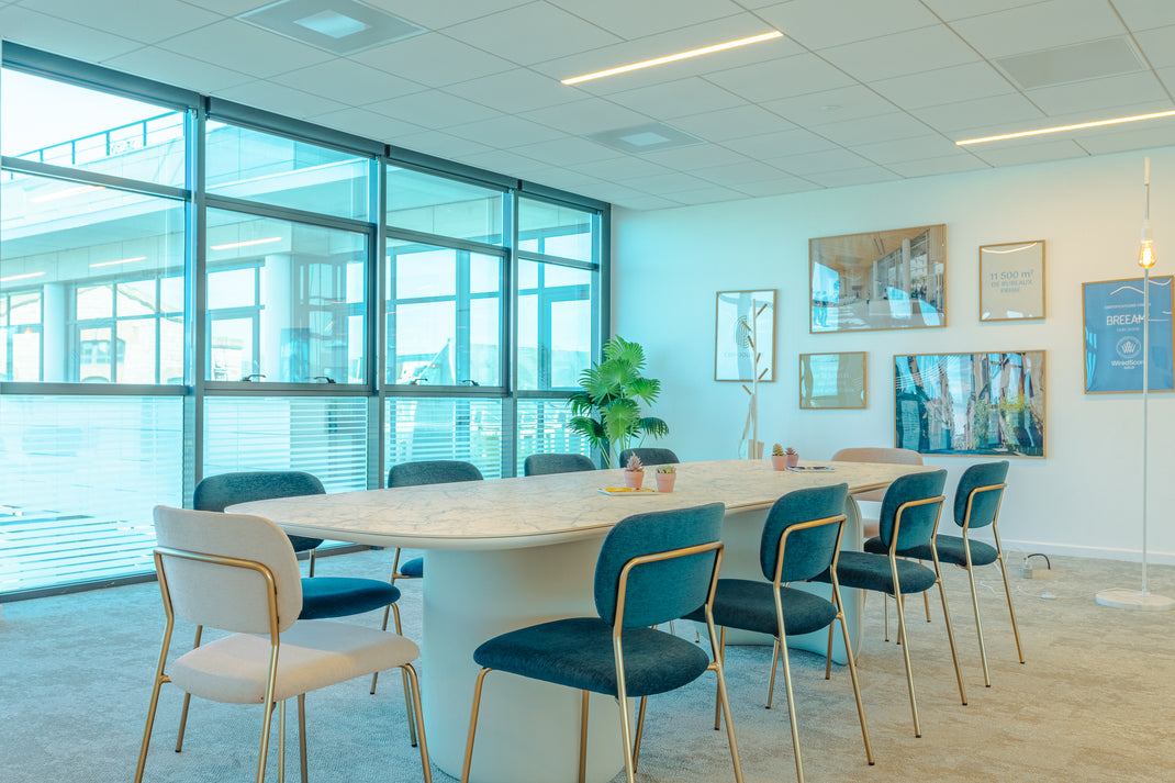 Modern conference room with white table and blue chairs near large windows.