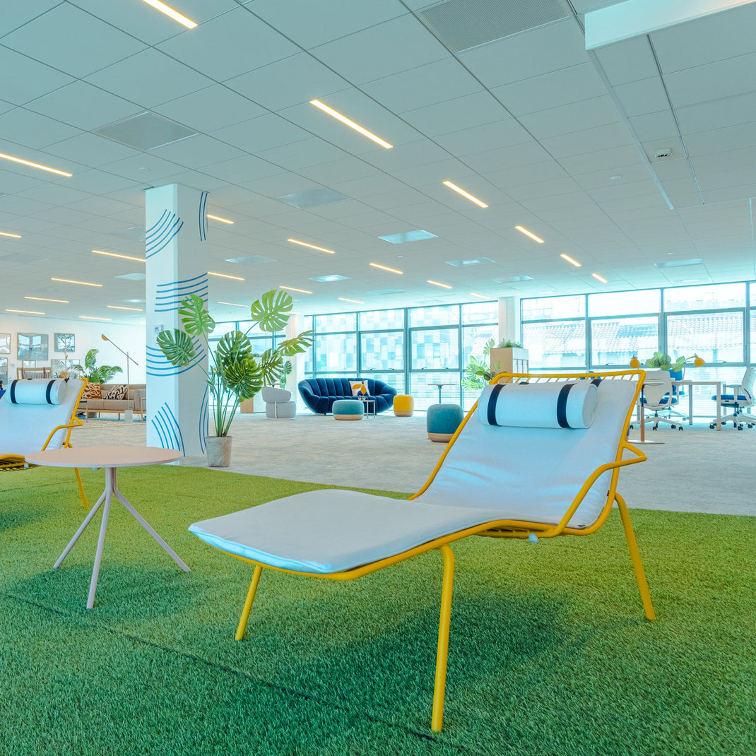 Modern office space with lounge chairs, tables, and plants.
