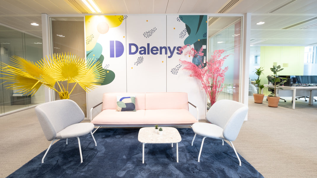 Modern office interior with a 'Dalenys' branded wall, sofa, and chairs.