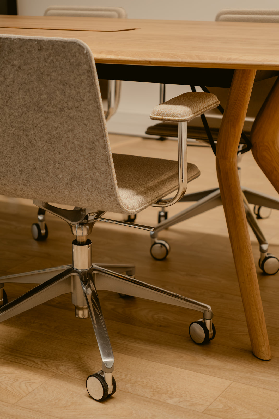 Close-up of a chair with wheels near a wooden table in an office setting