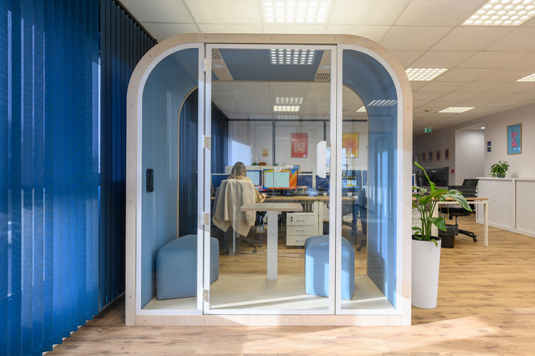 Modern office with a private booth and open-plan workstations.
