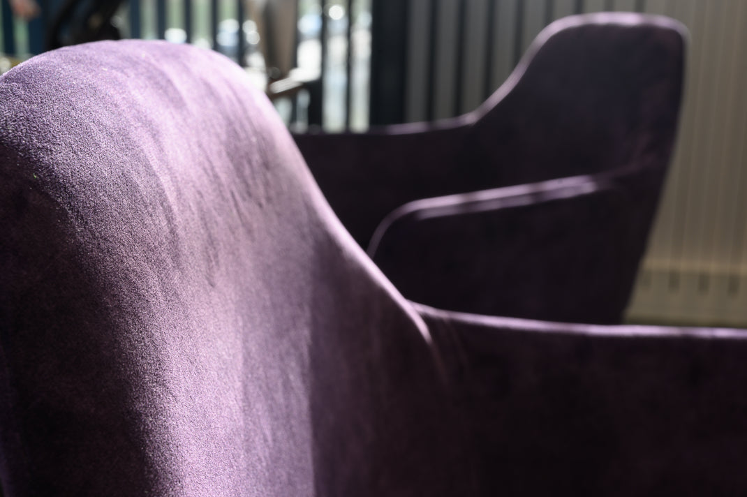 Close-up of a purple velvet armchair with a blurred background