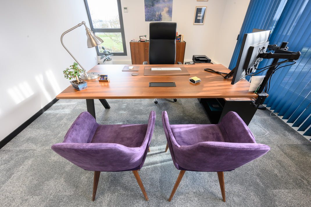 Modern office setup with a wooden desk, purple chairs, and a computer monitor.
