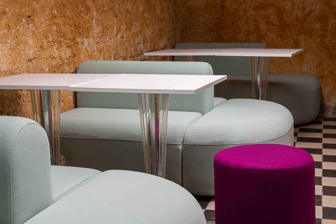 Modern cafe interior with tables, chairs, and a purple stool.