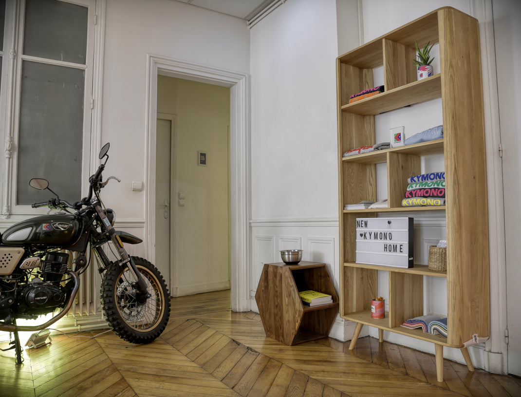 Motorcycle in n office room with wooden bookshelf and decor items