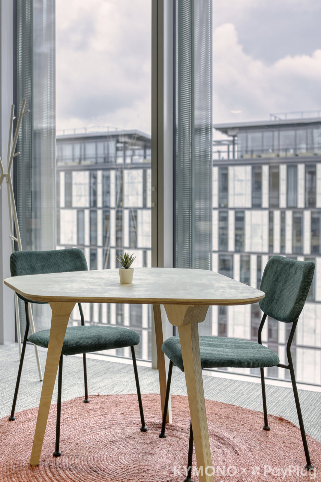 Dining table with two chairs in a modern room with large windows.