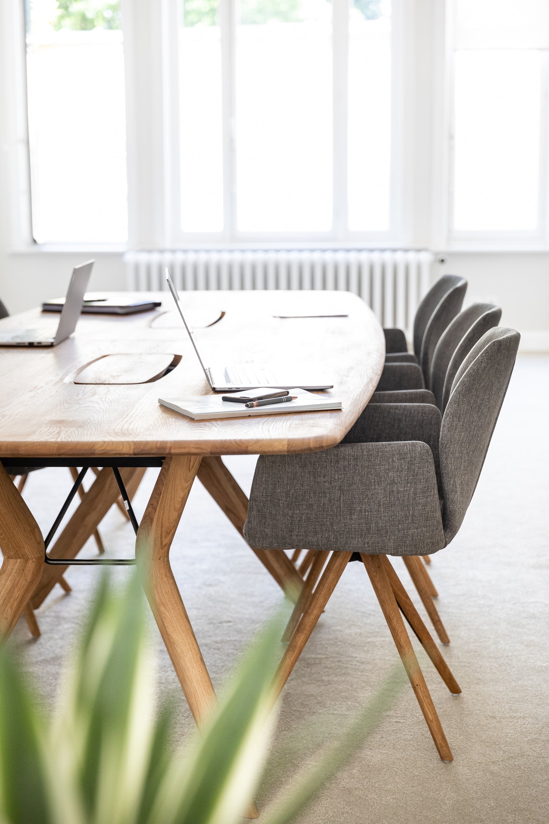 Modern office area with wooden table and gray chairs in a bright room.