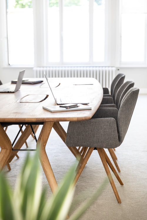 Modern office area with wooden table and gray chairs in a bright room.