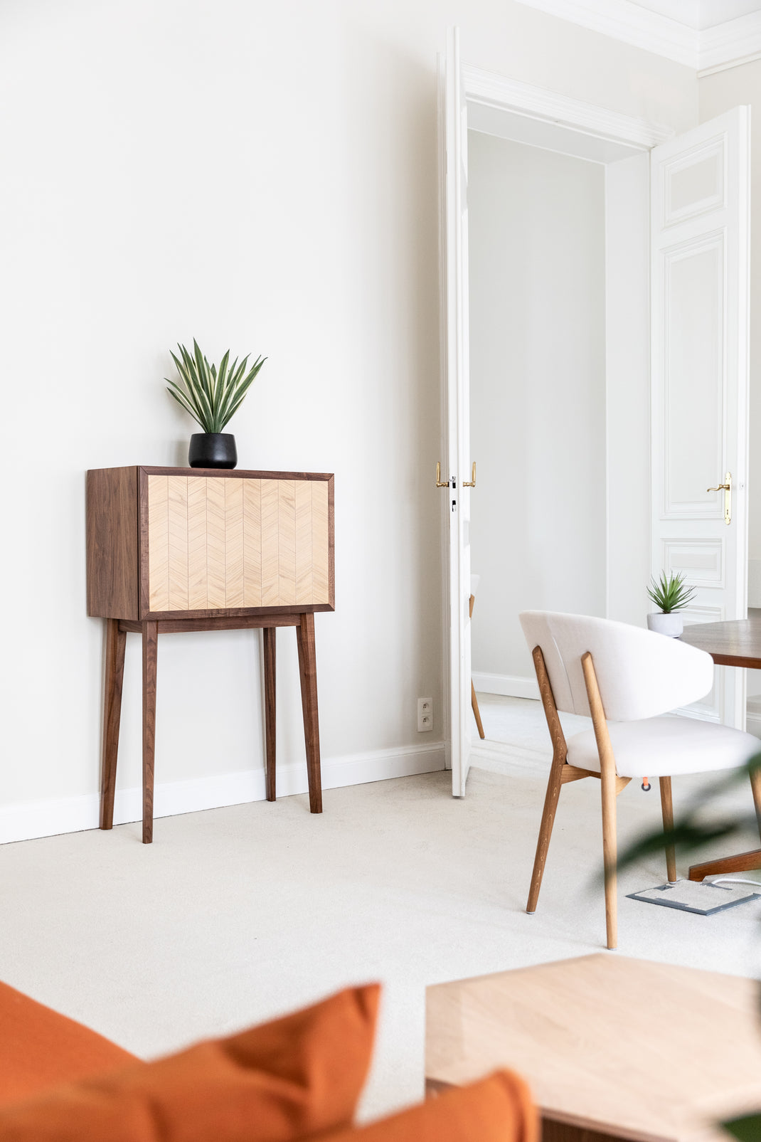 Modern interior with wooden cabinet, chair, and orange sofa.