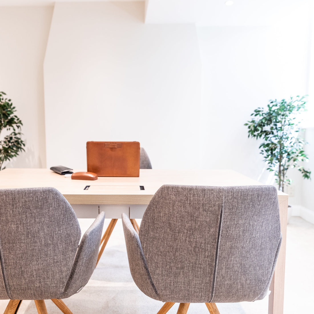 Two gray chairs in front of a white table with a laptop on a light-colored floor.