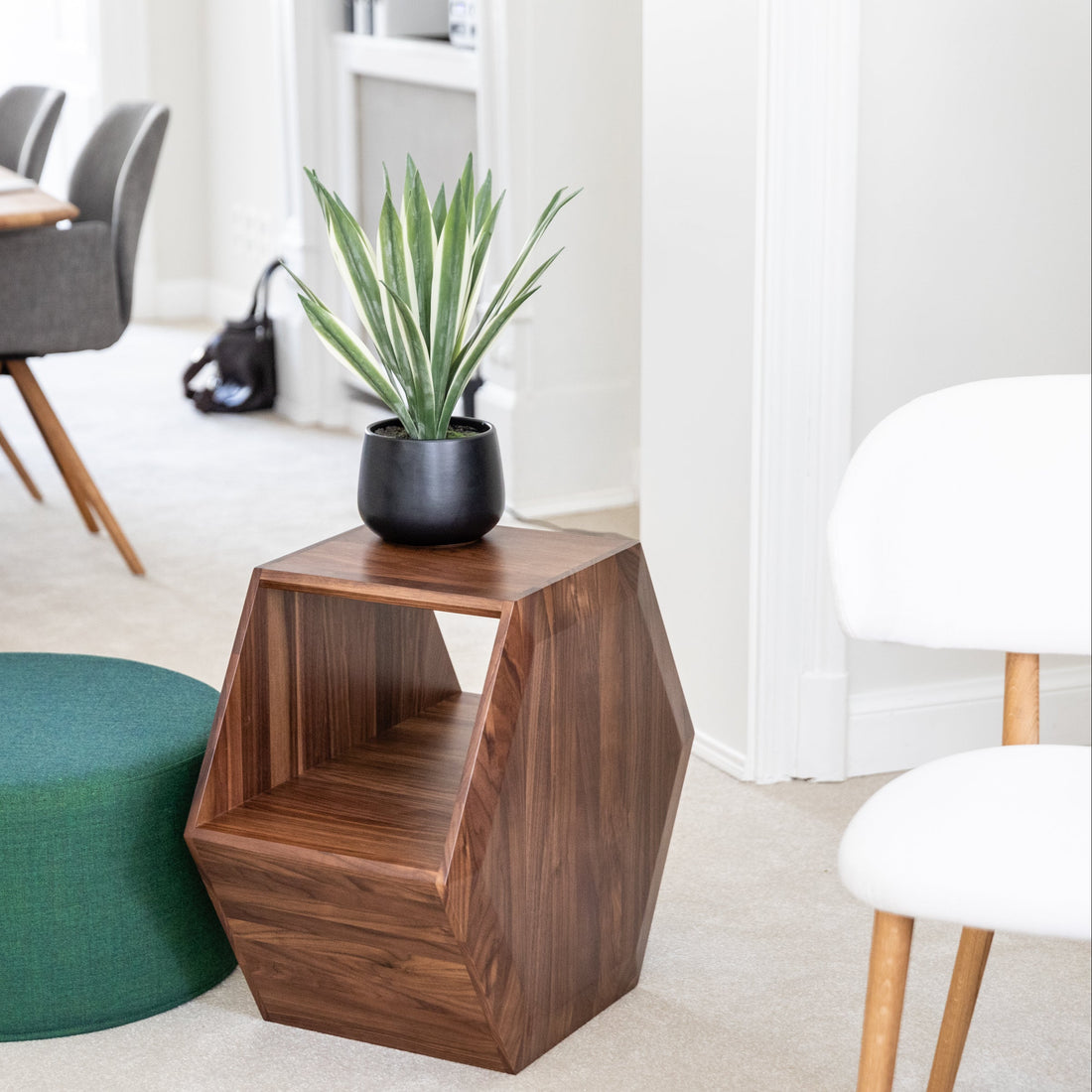 Modern room interior with a wooden side table, green ottoman, and a plant.