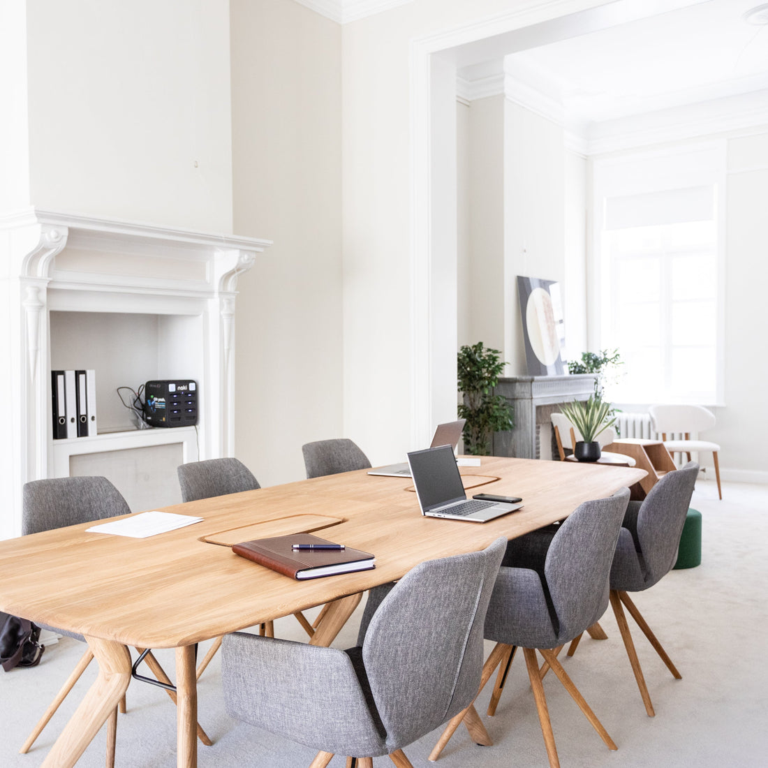 Modern conference room with wooden table and gray chairs in a bright office setting.