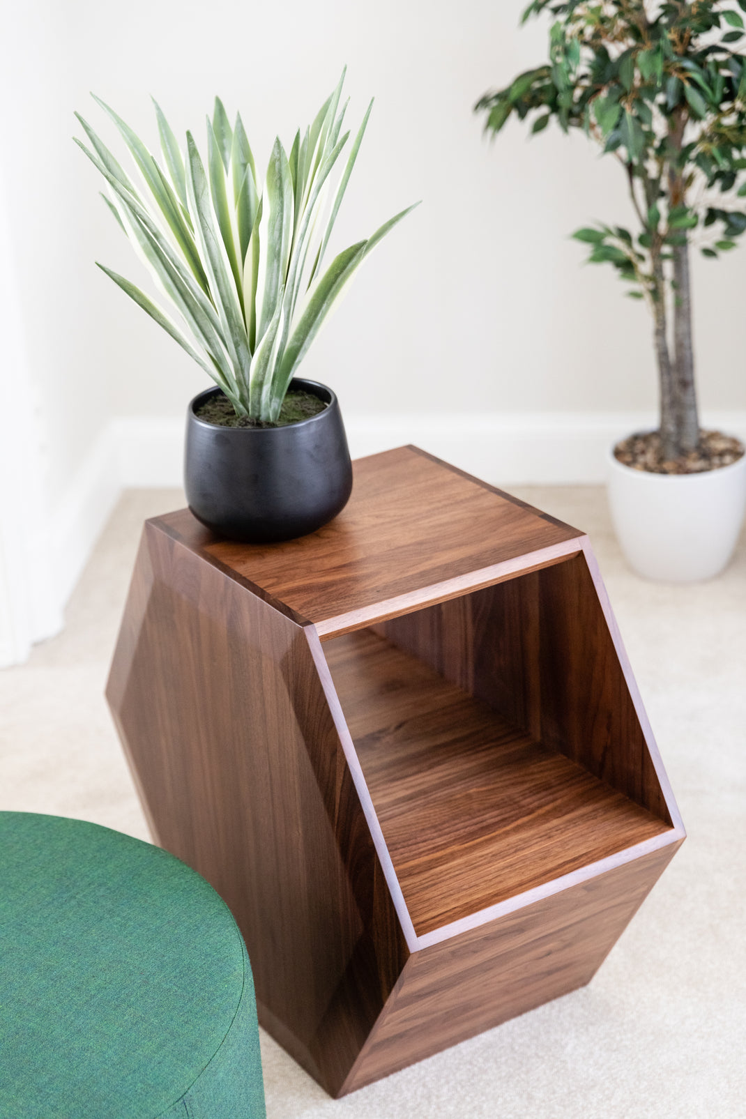 Wooden geometric side table with a plant on top in a minimalistic setting