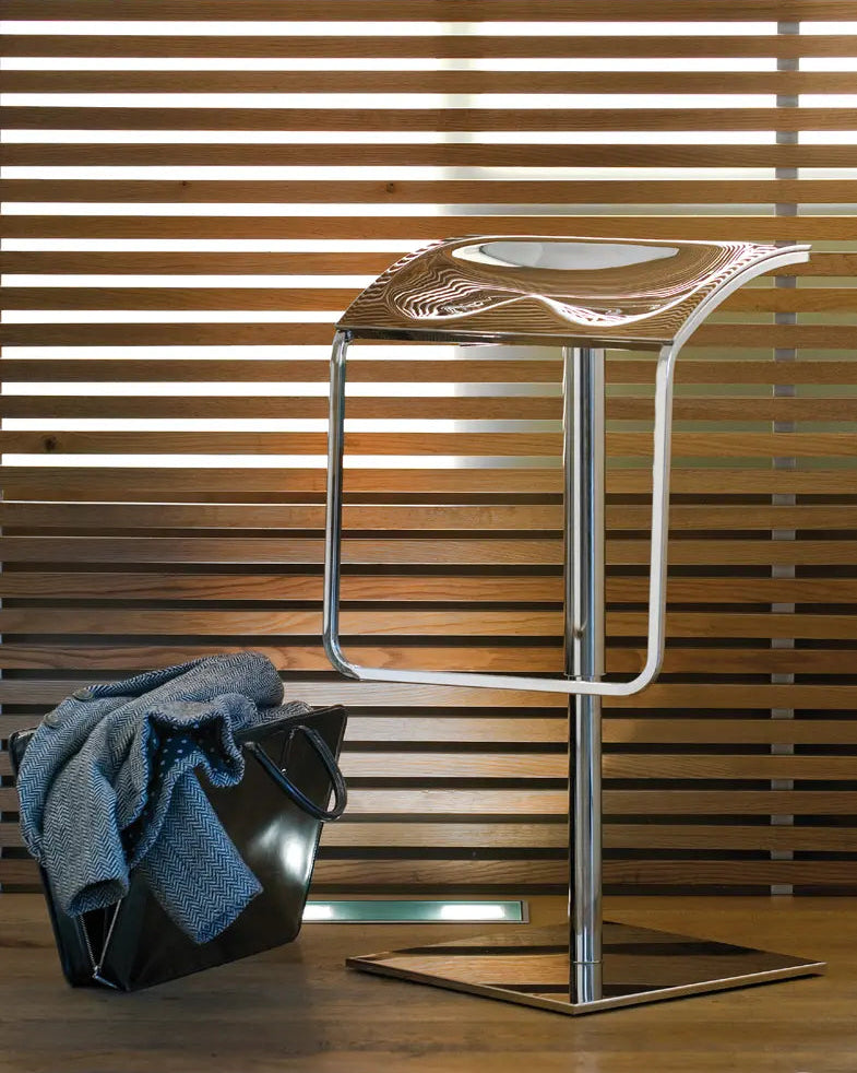 Modern bar stool with a metallic frame against a wooden slat wall.