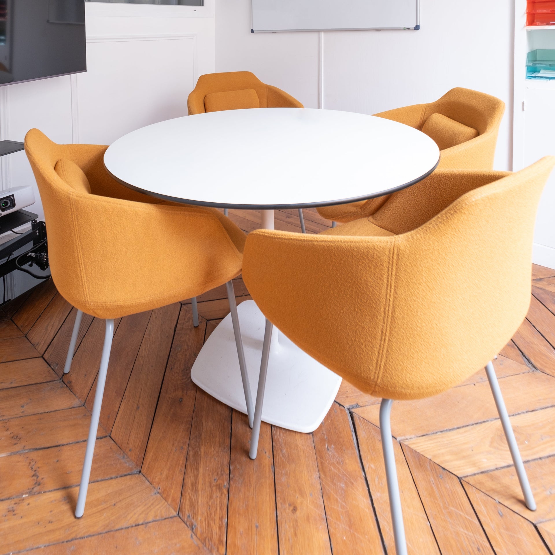 Round white table with orange chairs in a modern meeting room. 