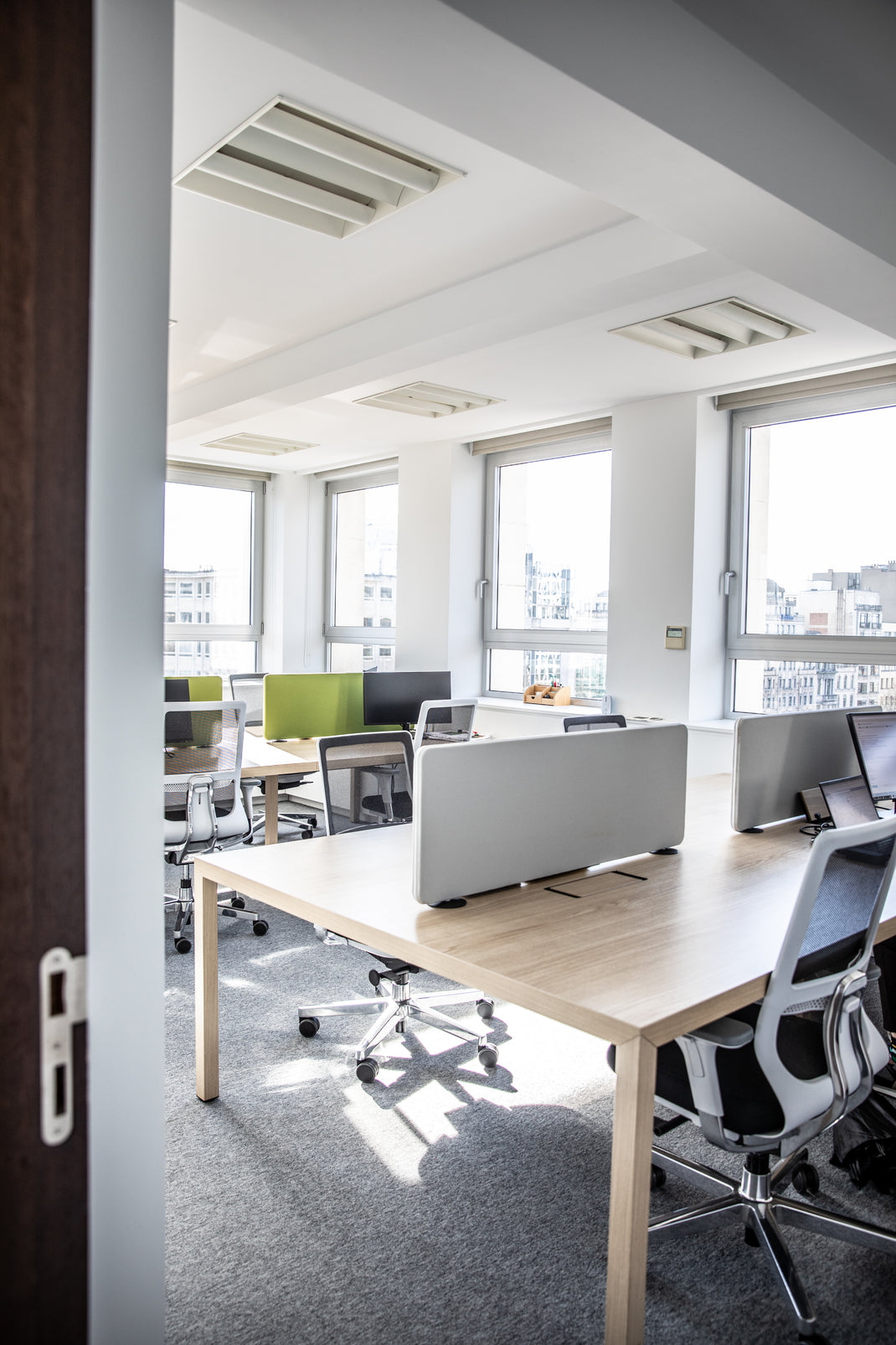 Modern office with large windows, desks, and chairs, sound proofing blocks. 
