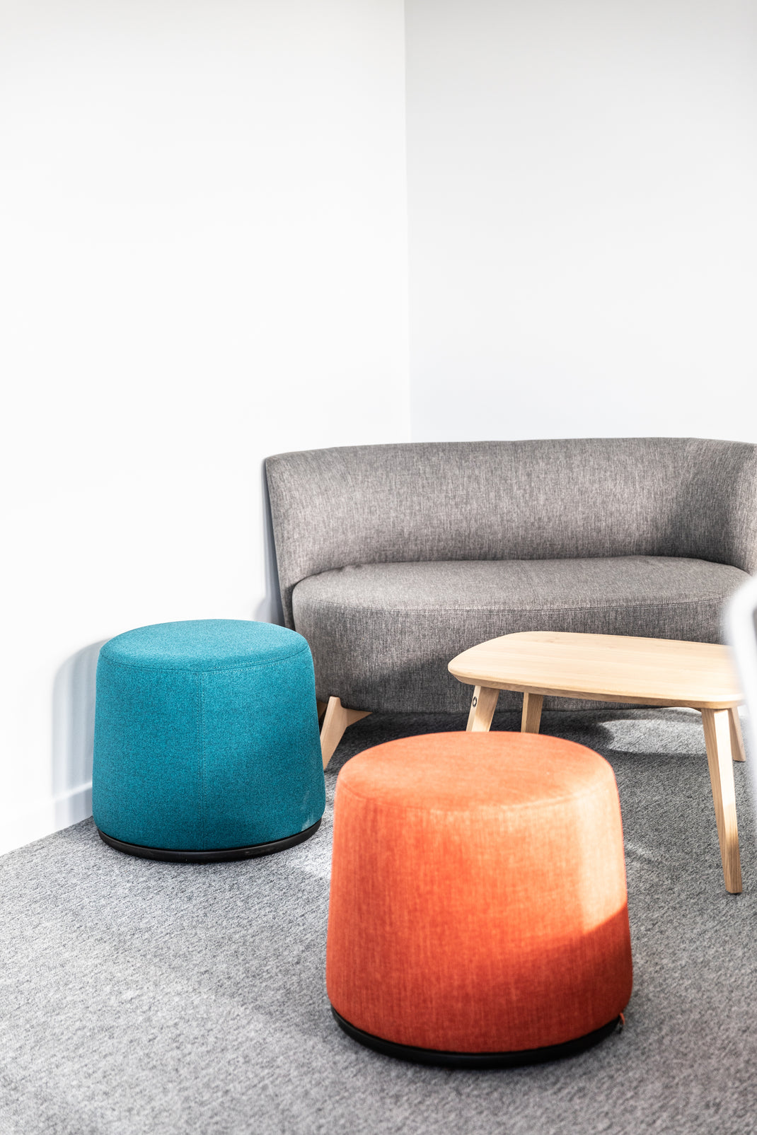 Gray sofa with two colorful stools in a minimalistic room.