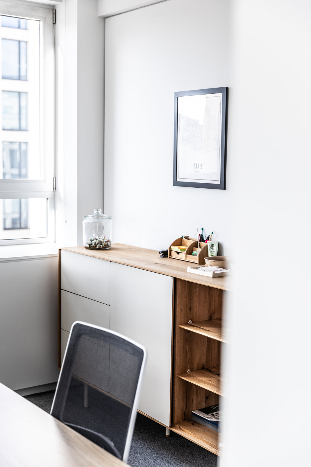 Small home office with white wall, wooden desk, and chair.