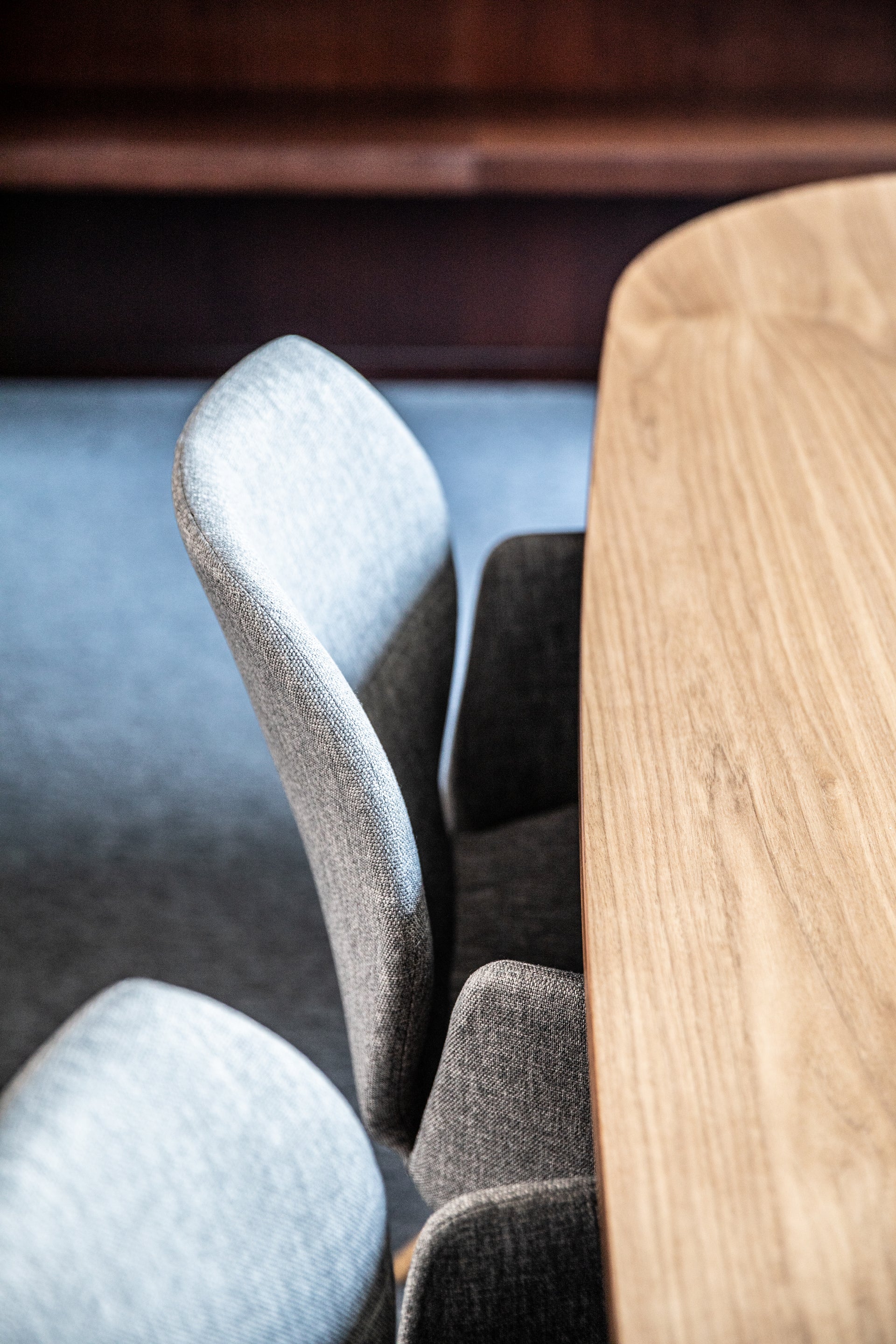Close-up of a wooden table and upholstered chairs in a room with wooden flooring.