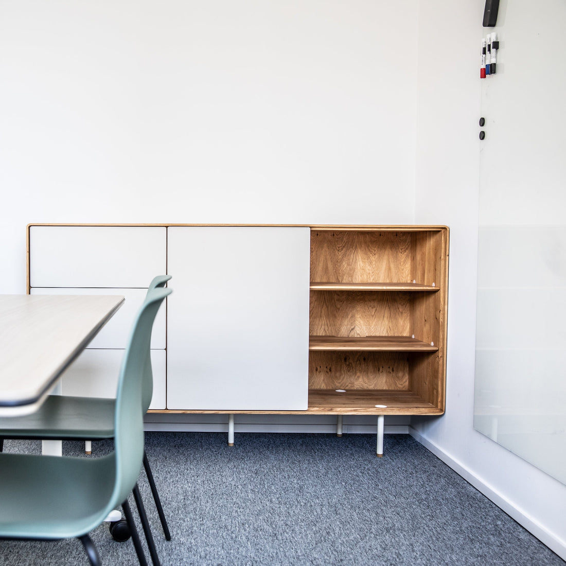 Modern office space with a table, chairs, and a wooden cabinet.