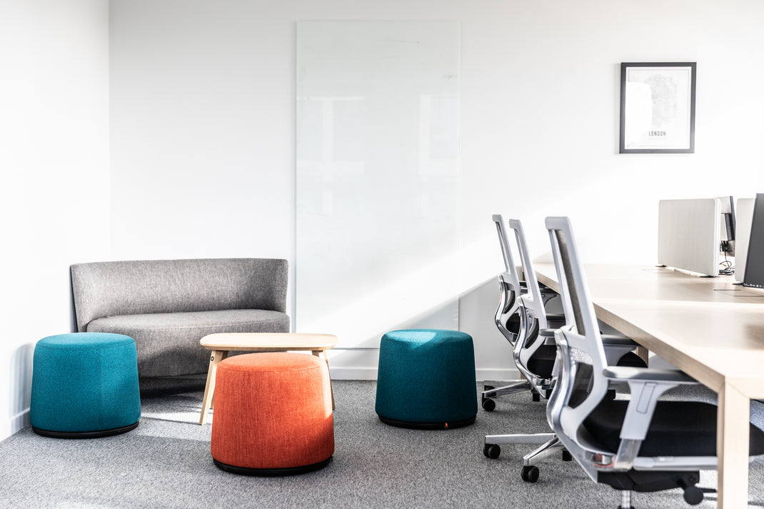 Modern office space with a desk, chairs, and colorful stools.