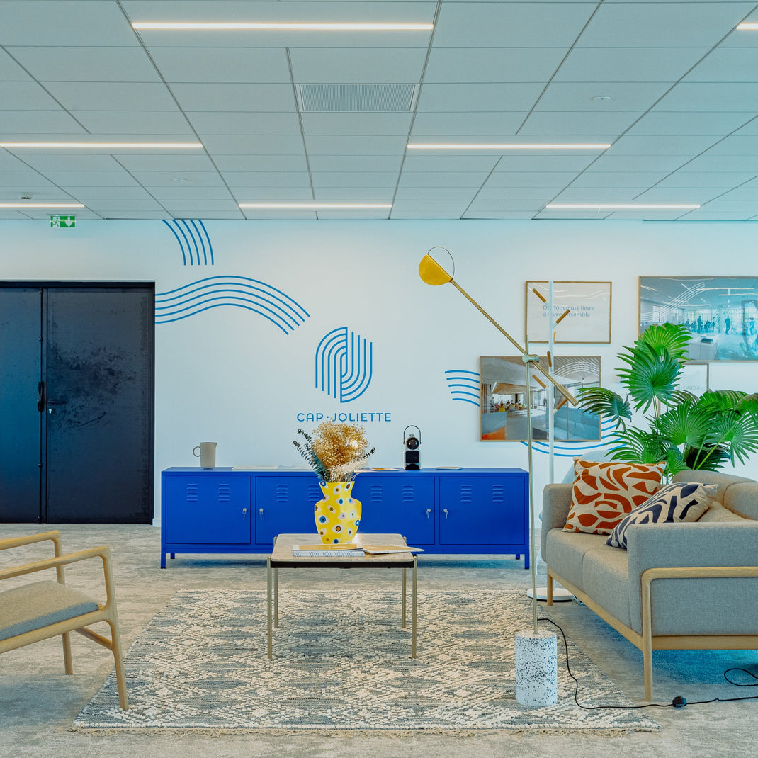 Modern office interior with blue cabinets, a sofa, and decorative elements.