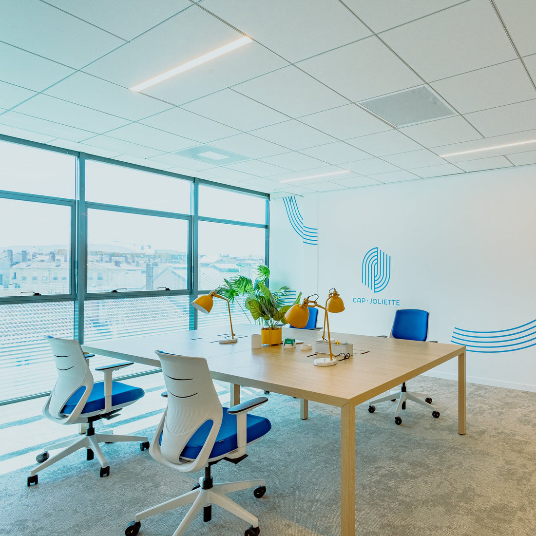 Modern office space with a large window, desk, chairs, and wall art.