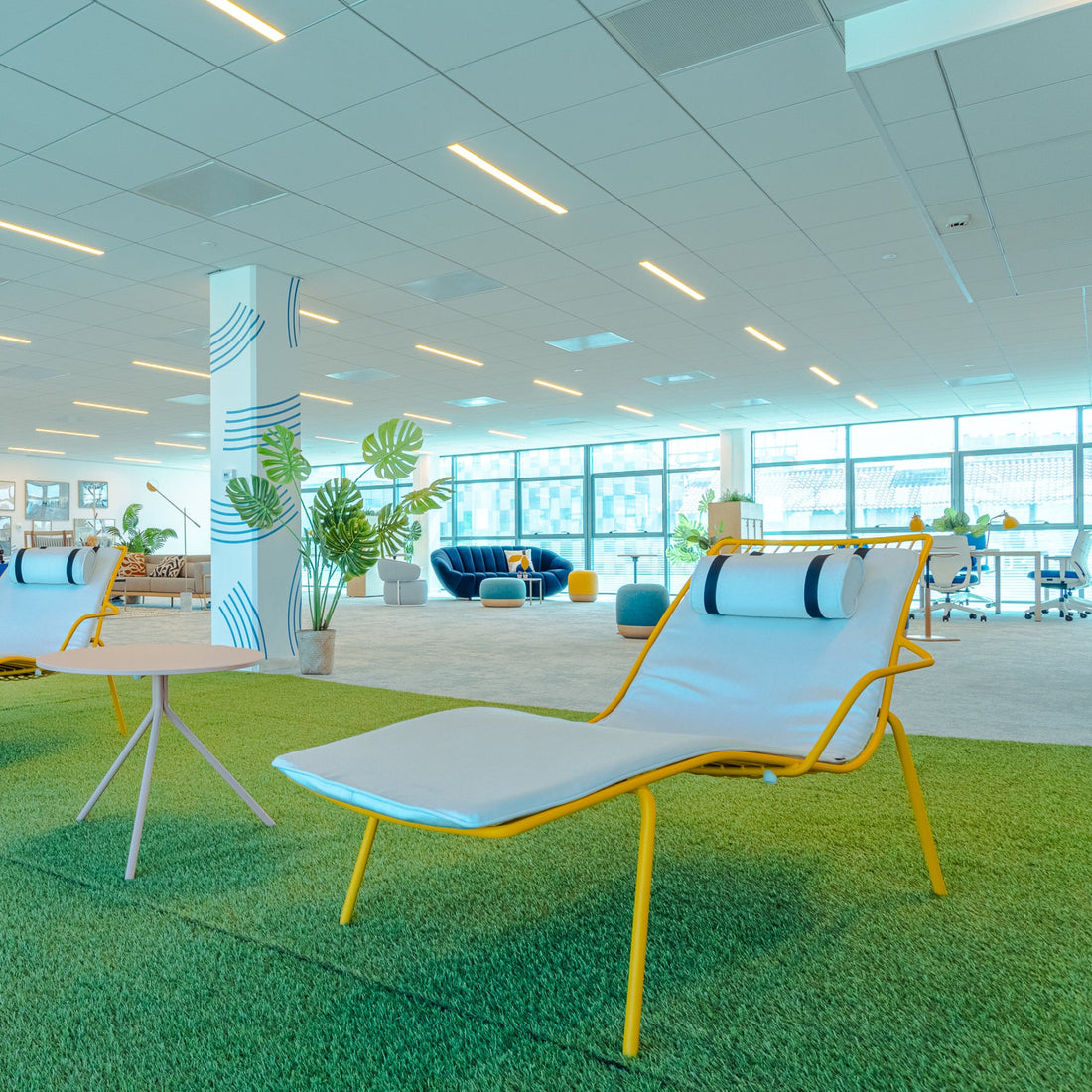 Modern office space with lounge chairs, tables, and plants.