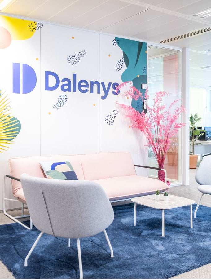 Modern office interior with 'Dalenys' branding on a wall, featuring furniture and decor.