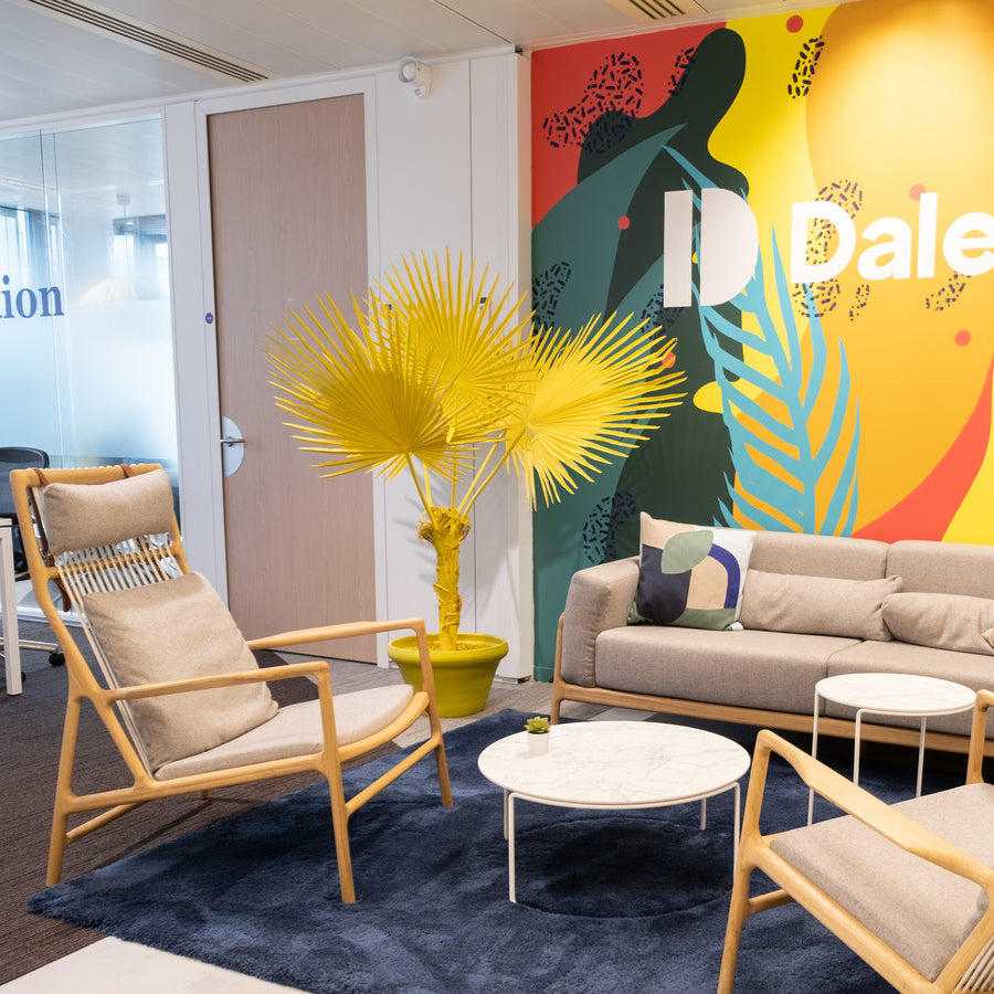 Modern office lounge with colorful wall art and furniture, featuring the Dalenys logo.