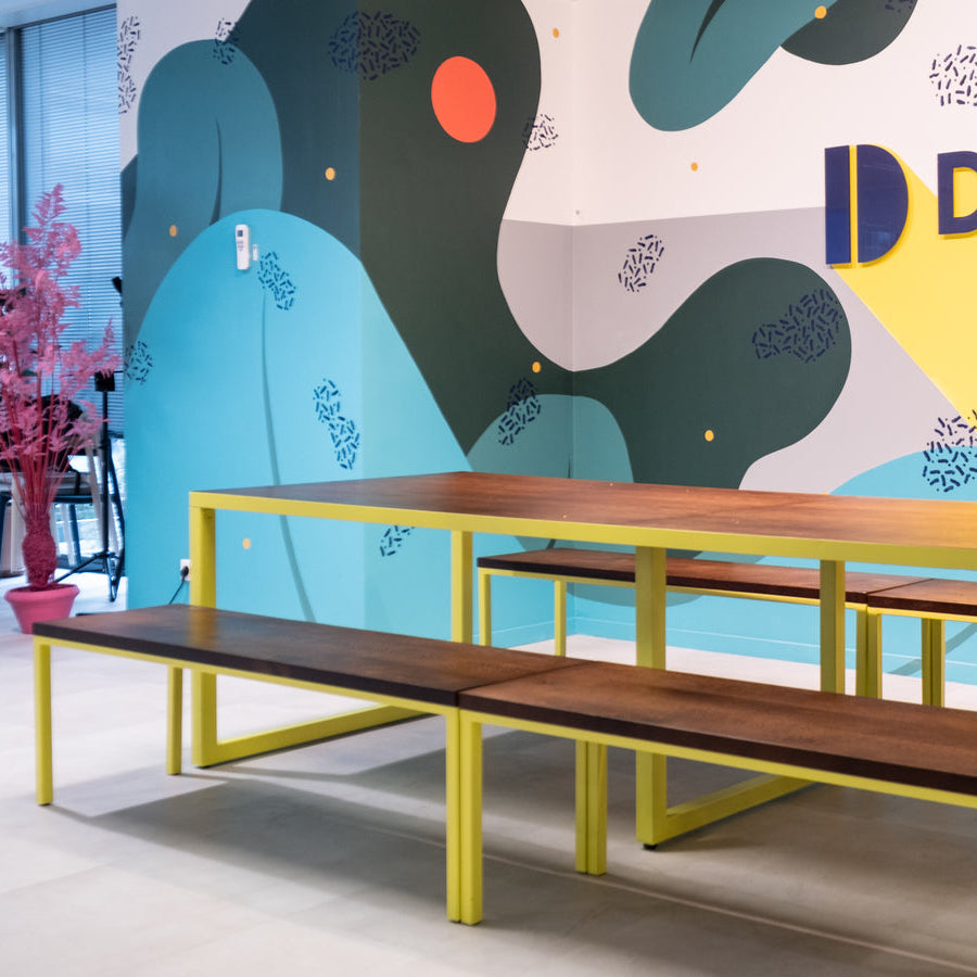 Wooden table with benches against a colorful wall featuring the Dalenys logo.