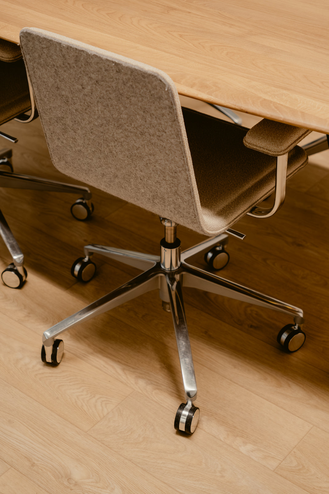 Greige office chair with metal base in front of a wooden desk