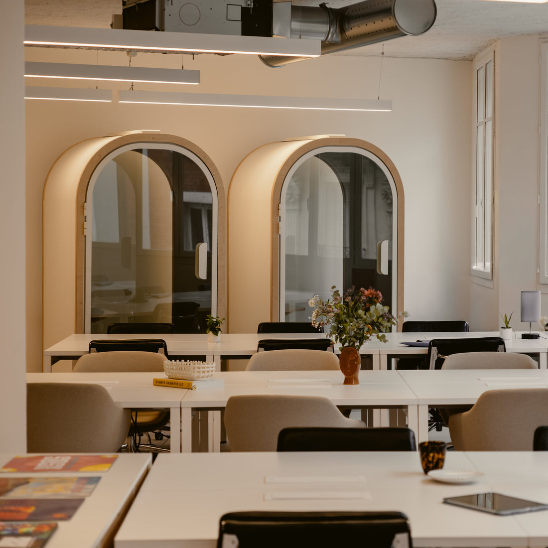 Modern office interior with tables, chairs, and decorative elements.