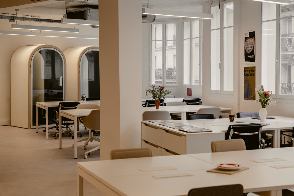 Modern office space with tables, chairs, and large windows.