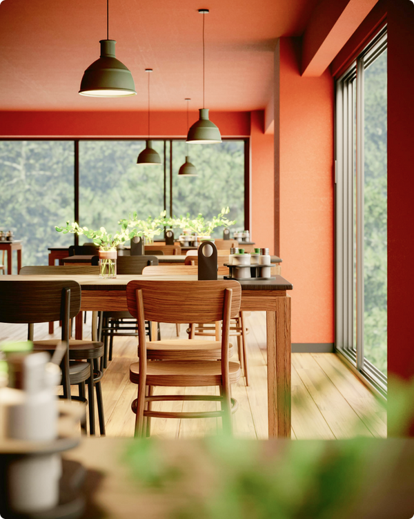 Dining area with wooden table and chairs against a red wall with large windows showing greenery outside.