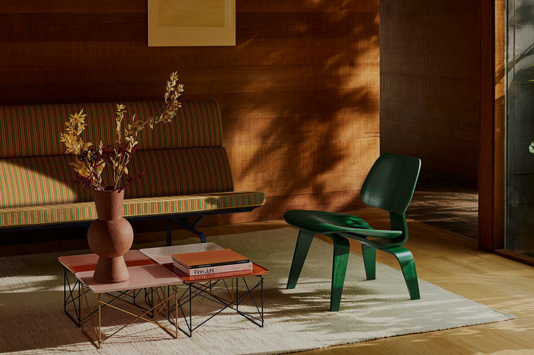 Modern green chair in a living room with a striped sofa and decorative items.