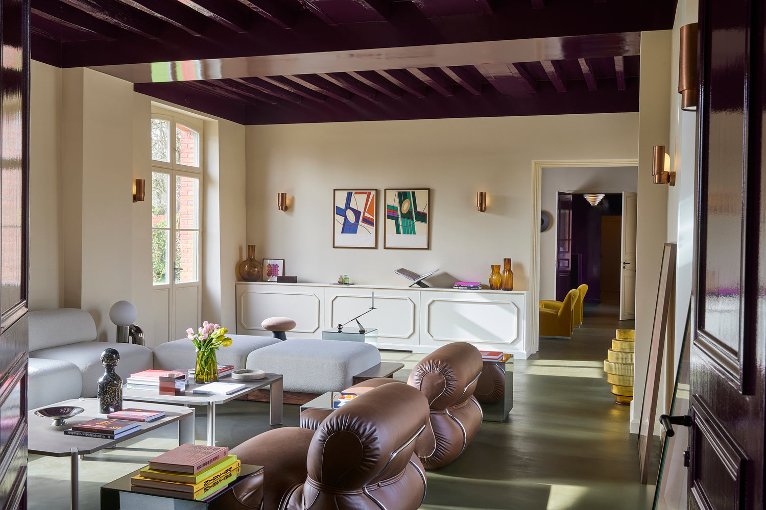 Modern living room with white furniture, purple accents, and decorative elements.