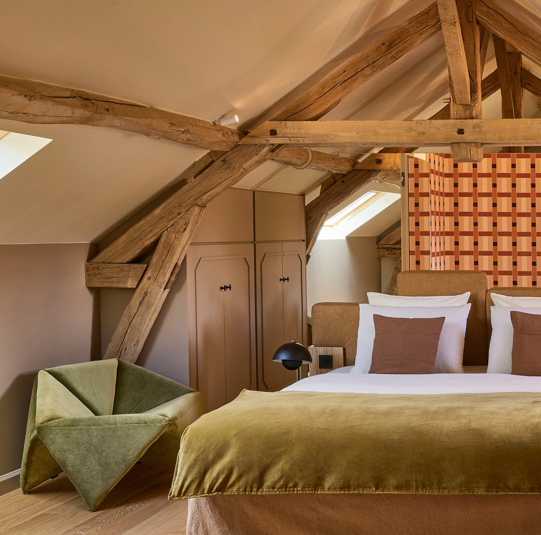 Bedroom with wooden beams and a bed with green blanket