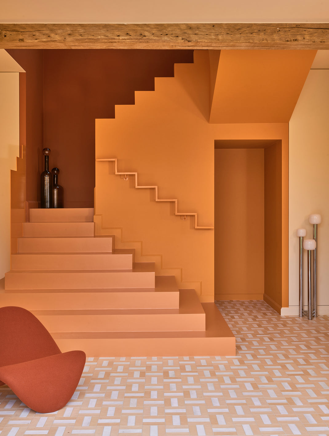 lobby area with concrete stairs in burnt orange and a deep orange lounge chair and vases. 