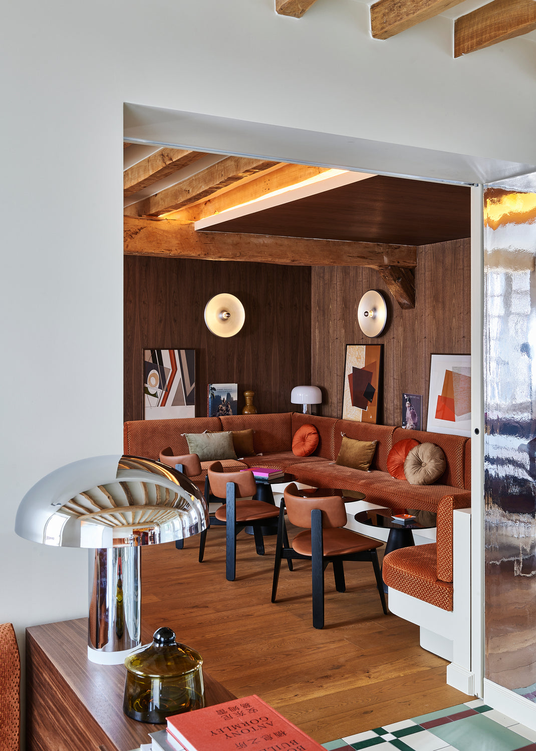 Modern dining break area with brown sectional sofa, wooden floor, and decorative wall art.