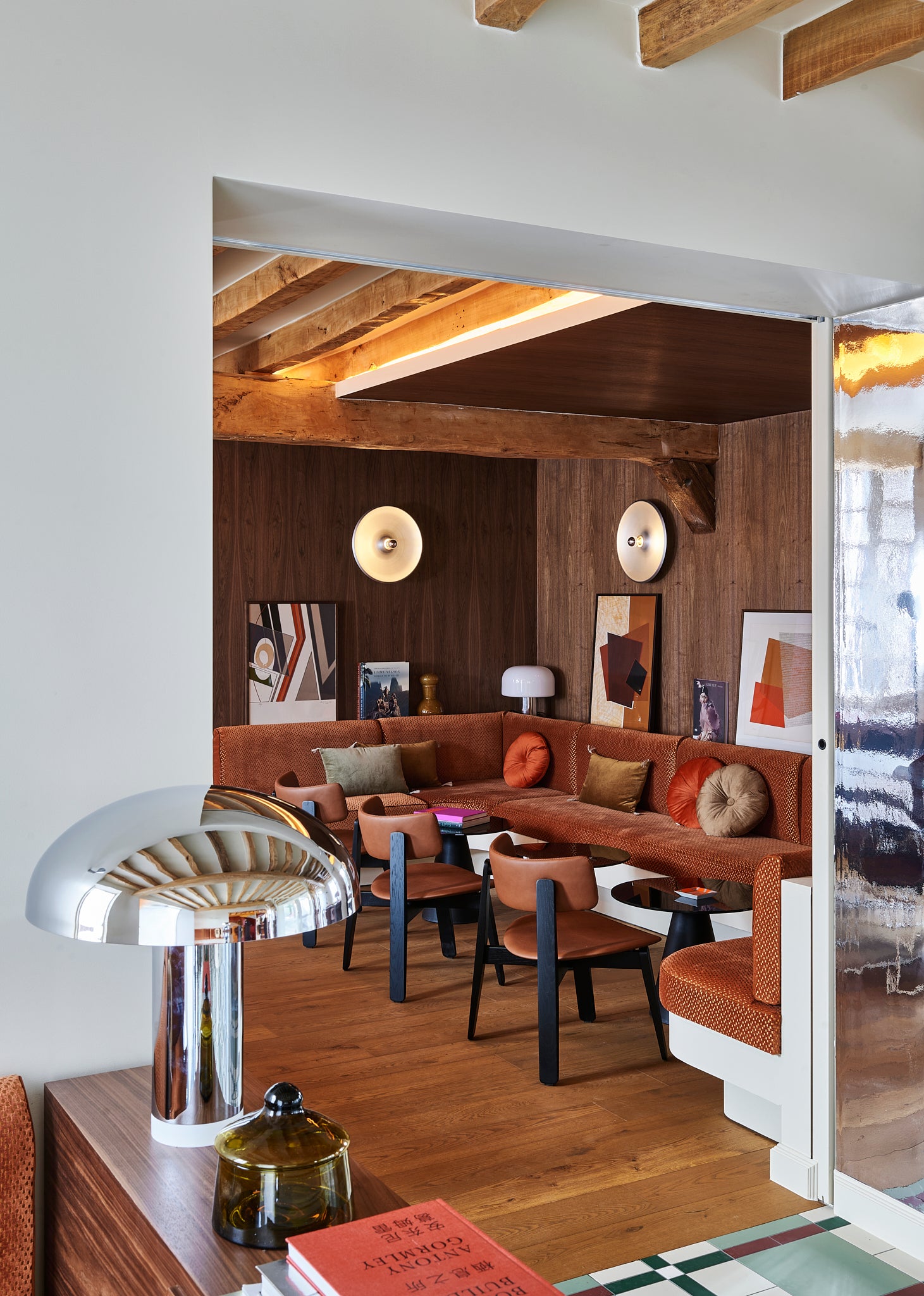 Modern dining break area with brown sectional sofa, wooden floor, and decorative wall art.