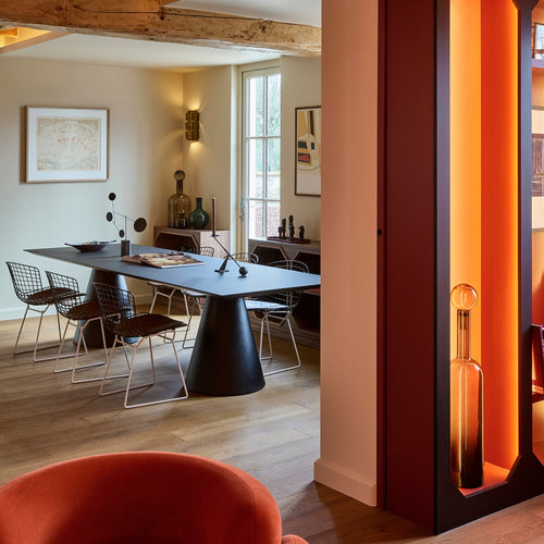 Modern interior design with a geometric orange partition, dining table, and chairs.