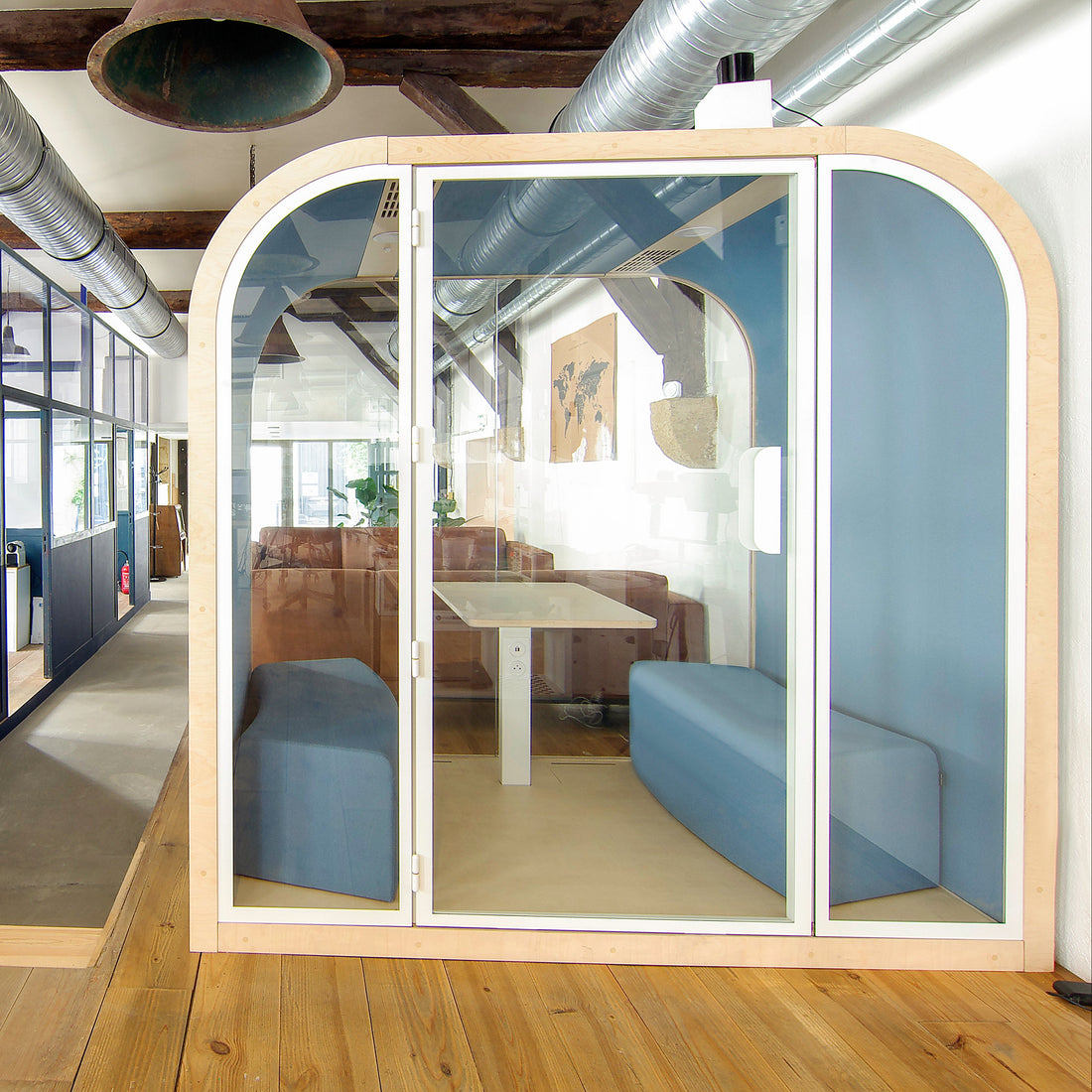 Modern office space with glass partitioned office pod and open workstations.