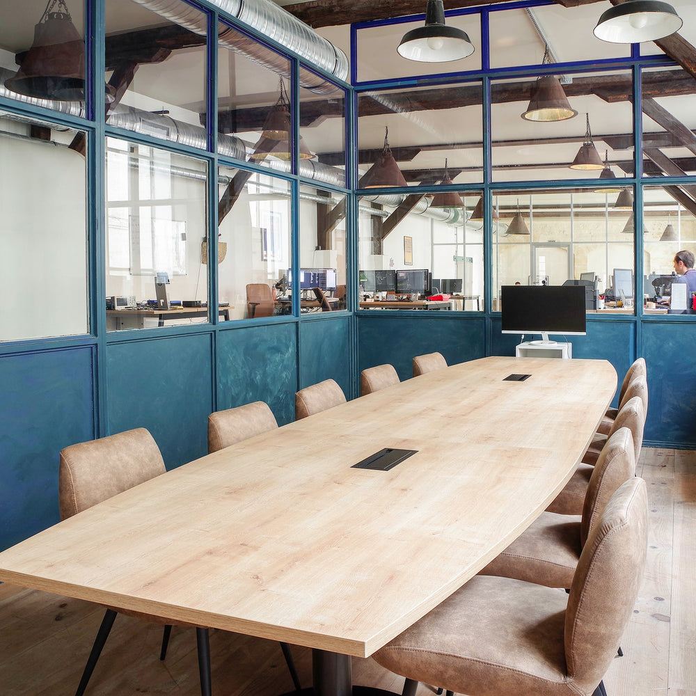 Long wooden conference table with chairs in a modern office setting.