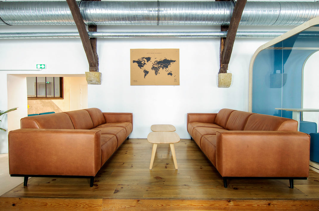 Modern living room with brown leather sofas and a world map on the wall.
