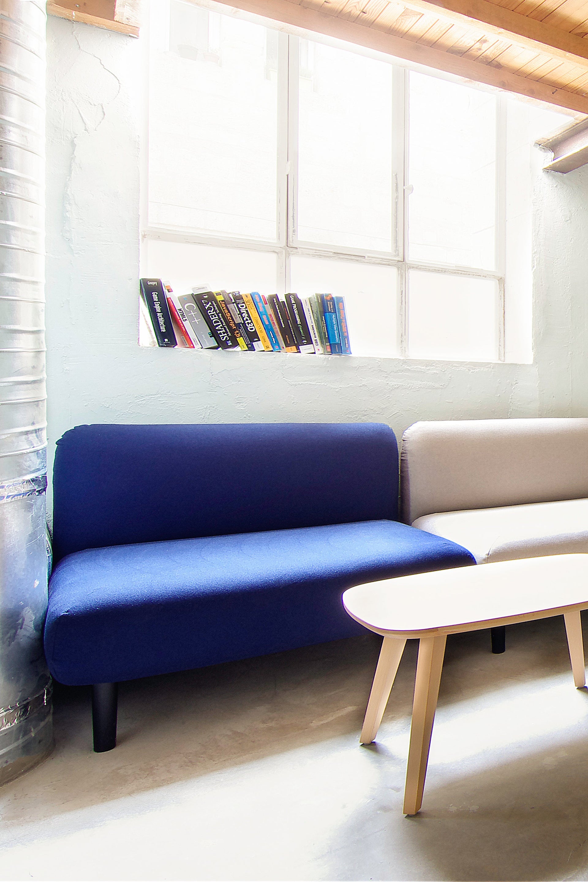 Modern lounge area in office with blue and white sofas and a wooden coffee table.