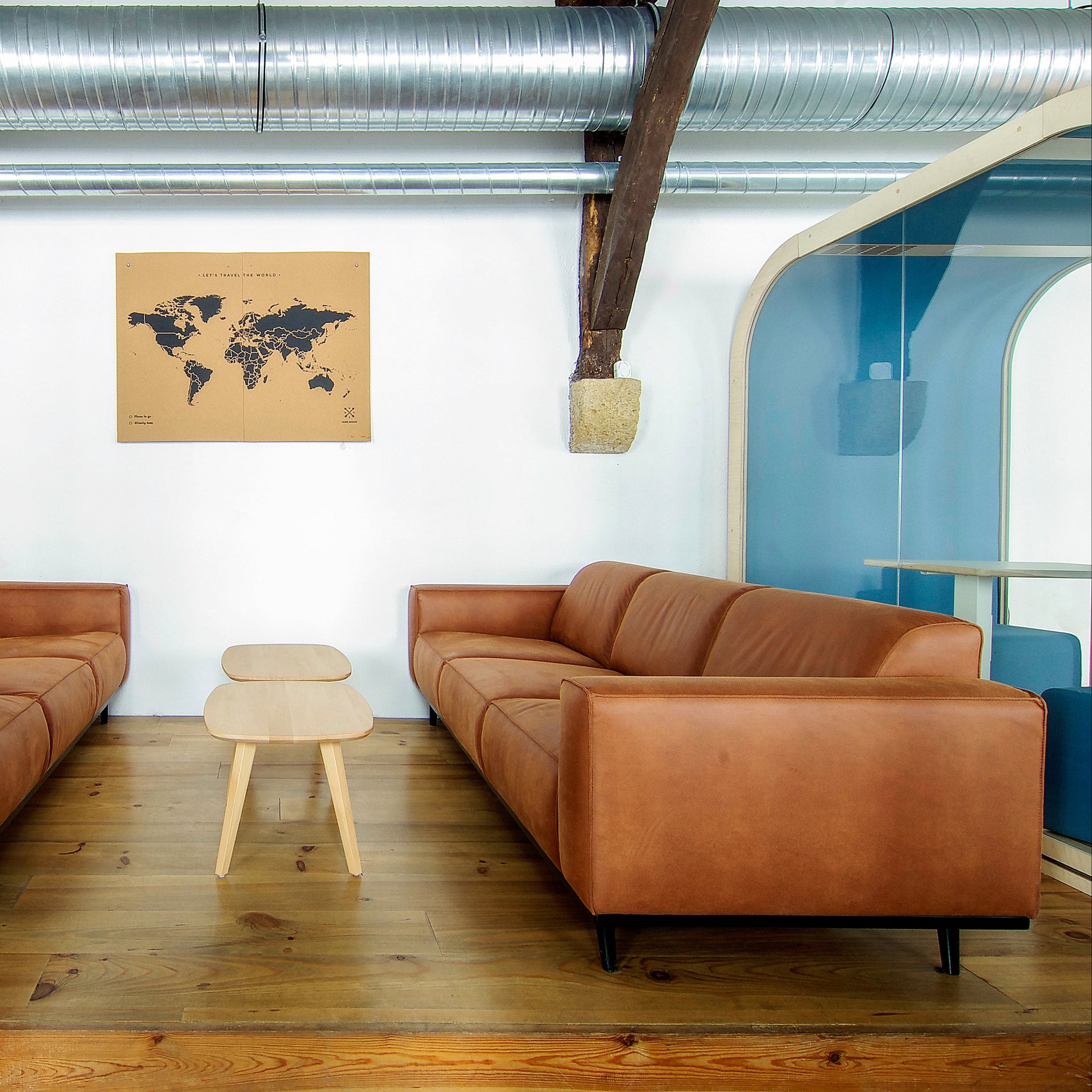 Modern lounge area in office space with brown leather sofas and a world map on the wall.